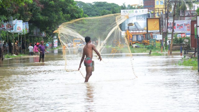A man tries to net fish in a flooded highway near Agartala Saturday. Image: Indigenousherald 