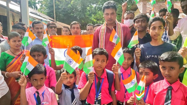 Former Tripura Chief Minister Biplab Kumar Deb gifts national flag to the school children at Bishalgarh in Sepahijala district Monday. Image: Twitter